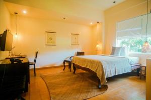 a bedroom with a bed and a desk and a window at iRoHa Garden Hotel & Resort in Phnom Penh