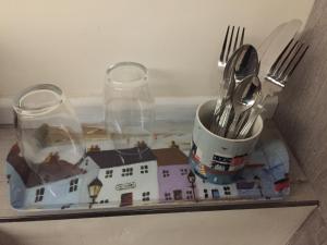 bandeja con utensilios y cubiertos en un estante en Self-contained small apt. Weymouth, en Weymouth