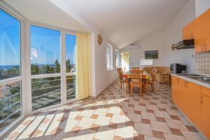 a kitchen with a table and chairs and a large window at Apartments Luaniva 50m from the see in Novalja