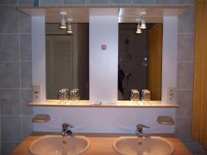 a bathroom with two sinks and two mirrors at Guest house Adonis in Bruges
