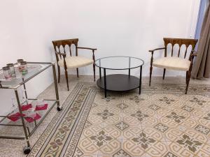 una stanza con due sedie e un tavolo in vetro e due sedie di Liberty Suites a Palermo