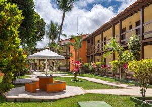 un patio en el complejo con bancos y sombrilla en Hotel Fênix, en Porto Seguro