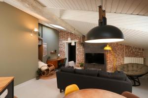 a living room with a black couch and a brick wall at 6 Rue d'Aubuisson in Toulouse