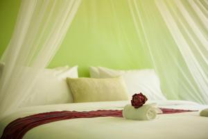 a white bed with a rose on top of it at iRoHa Garden Hotel & Resort in Phnom Penh