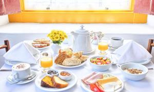 - une table avec des aliments pour le petit-déjeuner et du jus d'orange dans l'établissement Pousada do Ouro, à Parati