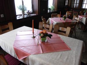 ein Esszimmer mit Tischen mit rosa Servietten und Kerzen in der Unterkunft Finken, Gästezimmer an der Rench in Oppenau