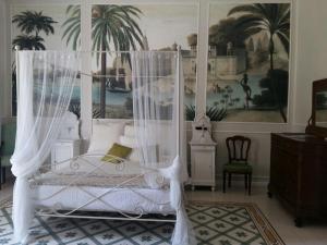 1 dormitorio con cama blanca con dosel y pintura en Villa Verganti Veronesi, en Inveruno