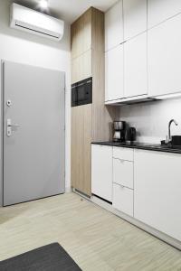 a kitchen with white cabinets and a white refrigerator at Compact Studios Słowackiego Avenue in Krakow