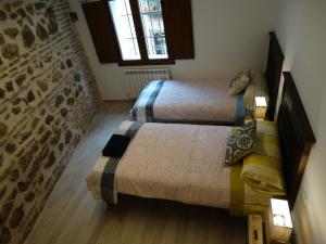 ein Schlafzimmer mit zwei Betten und zwei Fenstern in der Unterkunft El Muro de Piedra in Toledo