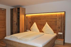 a bedroom with a large bed with a wooden headboard at Pension Michael in Saalbach Hinterglemm