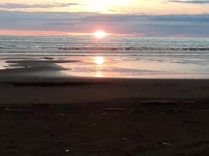 einen Sonnenuntergang am Strand mit der Sonne, die sich im Wasser spiegelt in der Unterkunft Cabaña El Bien Germina Ya in El Valle