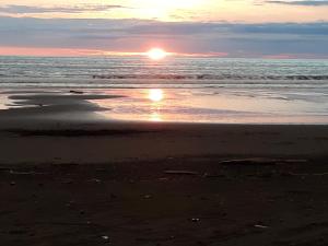 - un coucher de soleil sur une plage où le soleil se réfléchit dans l'eau dans l'établissement Cabaña El Bien Germina Ya, à El Valle