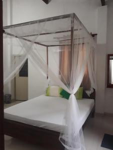 Bett mit Baldachin in einem Zimmer in der Unterkunft Arcade Beach Hotel in Induruwa