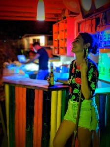 a woman talking on a cell phone while standing in front of a bar at Divanga Hostel in Taganga