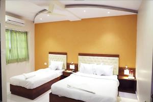 a bedroom with two beds and a yellow wall at Hotel Golden Hayyath Inn in Mumbai