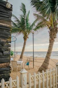 a beach with palm trees and a white fence at Lavinia Escapes in Mount Lavinia