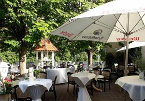 un ristorante con tavoli e sedie bianchi e un ombrellone di Hotel Schöne Aussicht a Gießen