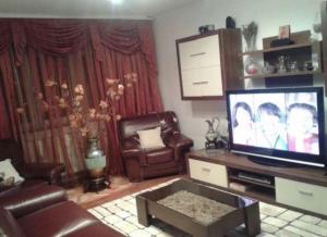 ein Wohnzimmer mit einem Flachbild-TV und Ledermöbeln in der Unterkunft Sweet Homme in Craiova