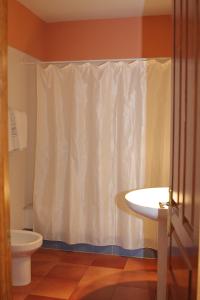 a bathroom with a toilet and a shower curtain at Hostal Esmeralda in Comillas