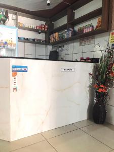 a white counter in a store with a vase of flowers at Hotel Fortaleza III Manaus in Manaus