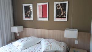 um quarto com uma cama com três fotografias na parede em Lindo Flat no Aldeias das Águas em Barra do Piraí