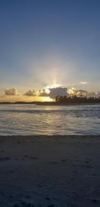 a beach with the sun setting in the distance at Pousada Água Viva in Ilha de Boipeba