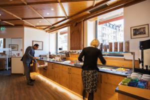 Duas pessoas numa cozinha a preparar comida. em Apartments Leipziger Hof em Innsbruck