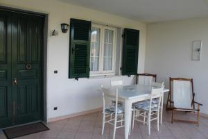 una mesa blanca y sillas en una habitación con puertas verdes en Casa Margubbio, en Ameglia