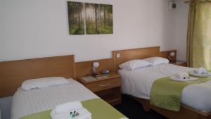 two beds in a hotel room with towels on them at The Beach Motel in Trearddur