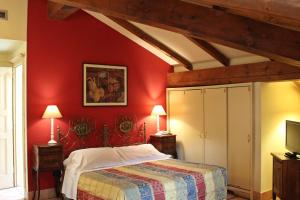 una camera da letto con pareti rosse, un letto e una TV di Albergo delle Drapperie a Bologna