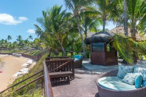 a resort with a bench and palm trees on the beach at Condomínio Nannai Residence - Anchova 01 in Porto De Galinhas