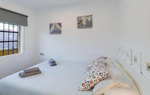 ein weißes Schlafzimmer mit einem Bett mit Kissen darauf in der Unterkunft Apartamento Los tres soles in Málaga
