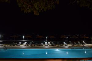 een zwembad met stoelen en parasols in de nacht bij Apolafsi in Lixouri