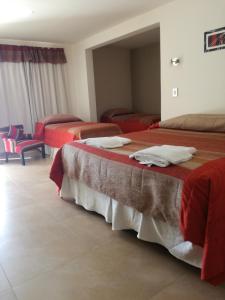 a hotel room with three beds with red sheets at Hotel Parador Ruta 40 in Gobernador Gregores