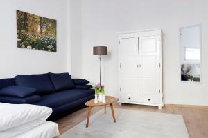 a living room with a blue couch and a table at BLISSE by ROCKCHAIR Apartments l SUPERHOST Status l 5 Schlafzimmer 3 Bäder 3 Balkone l Family & Business Flair welcomes you! in Berlin +4 photos