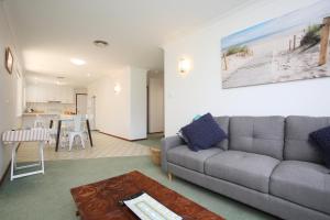 uma sala de estar com um sofá cinzento e uma mesa em BILL'S em Coffs Harbour