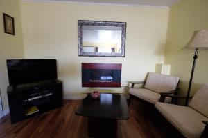 a living room with a couch and a tv and a table at Motel Canadien in Trois-Rivières