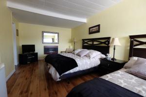 a bedroom with two beds and a flat screen tv at Motel Canadien in Trois-Rivières
