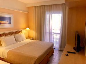 a hotel room with a bed and a television at Flat Partic Hotel Jurere Beach Village in Florianópolis