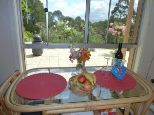 una mesa con un bol de fruta y una botella de vino en Murrindindi, en Kallista