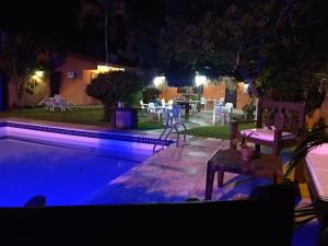 einen Pool in der Nacht mit einem Tisch und Stühlen in der Unterkunft Pousada Bella Vida Geriba in Búzios