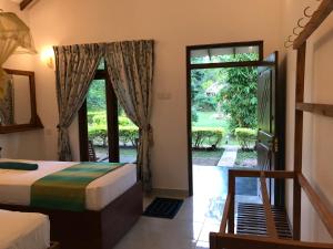 a bedroom with a bed and a door to a yard at Liyon Rest sigiriya in Sigiriya