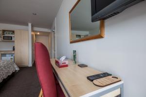 - un bureau avec une chaise rouge et un miroir dans l'établissement The Westhaven Motel, à Glacier Fox