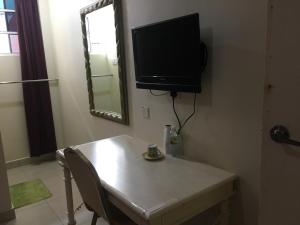 um quarto com uma mesa e uma televisão na parede em Hotel Morning Glory em Kudat