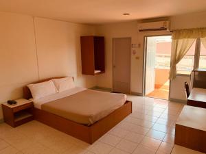 1 dormitorio con 1 cama y puerta a un balcón en Baansilp Hotel, en Chiang Rai