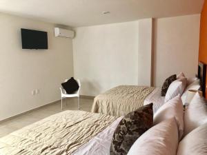 Cette chambre comprend 2 lits, une télévision et une chaise. dans l'établissement ZAMORA EJECUTIVO EXPRESS, à Zamora de Hidalgo