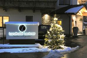 a christmas tree in front of a building with a sign at Landhotel Lechner Appartements in Kirchberg in Tirol