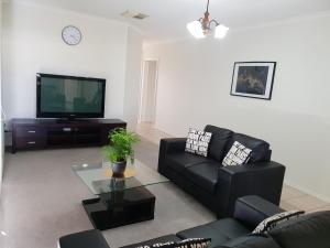 Una sala de estar con un sofá negro y un televisor. en SAN Mateo, en Mildura