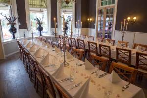a banquet hall with tables and chairs with white tablecloths at Parkhotel Hugo de Vries in Lunteren