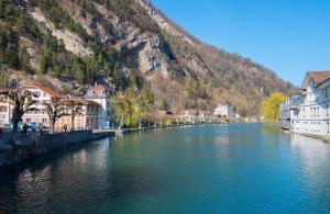 a river in a town with houses and a mountain at Golden River in Unterseen